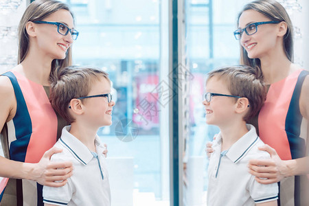 母亲和儿子在验光师商店的镜子图片