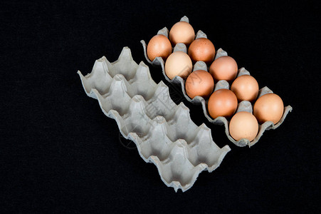 纸箱中的十个鸡蛋和黑色毛毡背景上图片