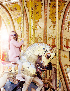 可爱的小女孩戴着太阳镜骑着旋转木马图片