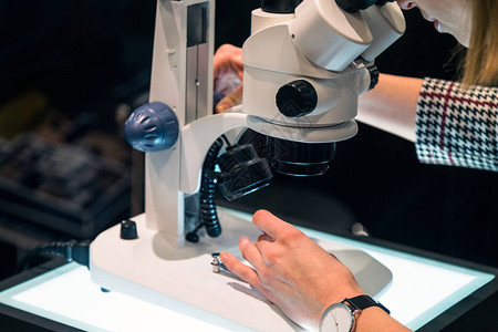 年轻女科学家在实验室通过显微镜进图片