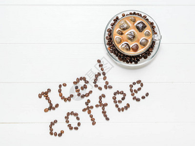 铭文冰咖啡和白桌上的一杯成品饮料提神醒脑的咖啡豆和牛奶饮品从顶部图片