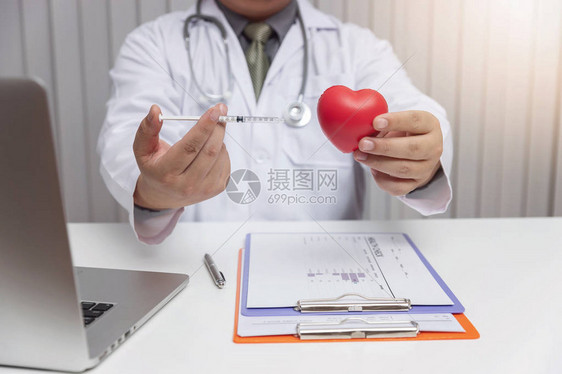 保健和医疗概念医生持有注射针头和心脏球图片