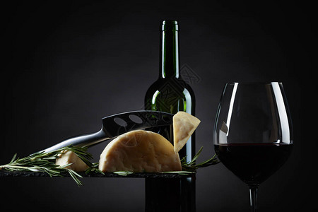 黑色背景上的羊奶酪配迷迭香和红酒背景图片