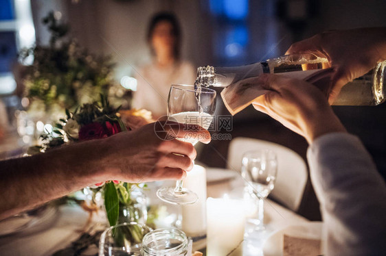 在晚上的室内聚会上将香槟倒进玻璃杯里面有一大片无法图片