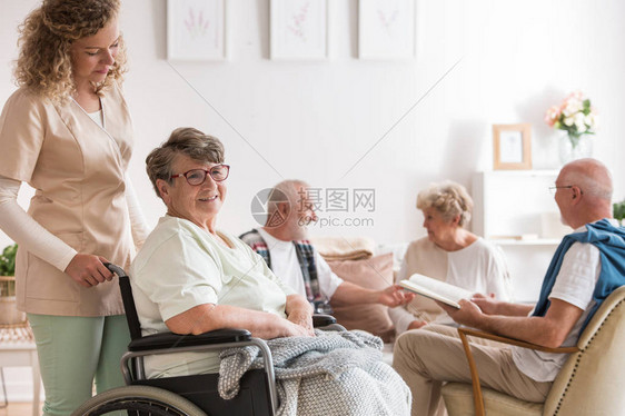年轻漂亮的照顾者和积极的老年妇女坐在老人疗图片