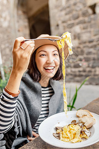 快乐的亚洲女人在户外意大利餐厅图片