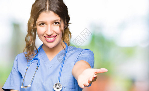 年轻的成年医生女人穿着医疗制服微笑着友好地握手作为问候和欢迎图片