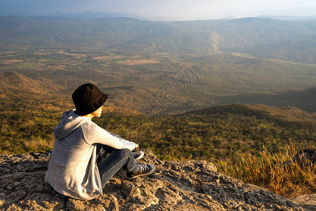 一位坐在岩石山上的女人仰望着景色优美的自然风景和图片