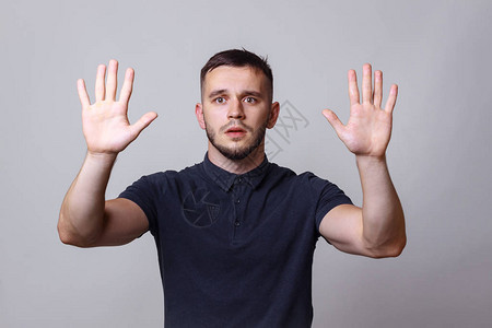 一位年轻人的演播室肖像用献身这个表达方式在他面前举手和谐谦逊抗议幽默图片