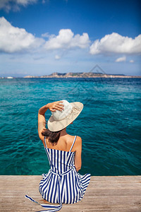 在意大利撒丁岛的海码头上放松快乐的女士在帽子中脱图片
