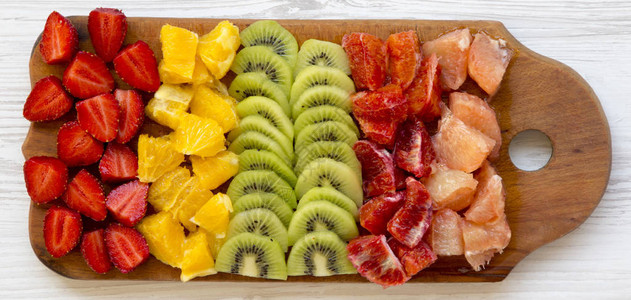 切碎的水果排列在白色木质表面的切菜板上图片