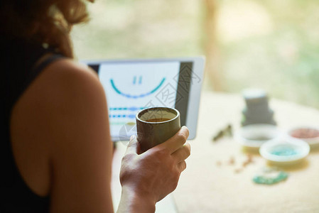 年轻女握着咖啡杯和数字平板电脑图片