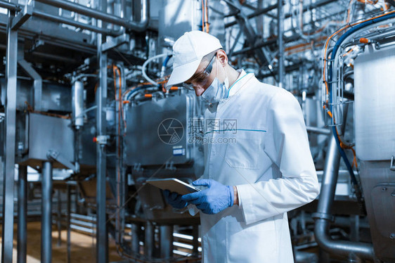 集中的技术人员站在乳制品厂的生产部门图片