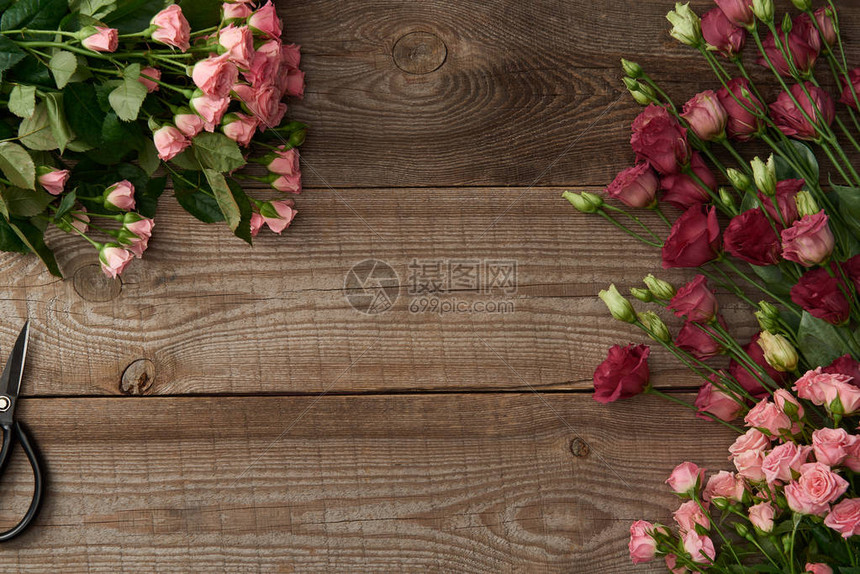 木制表面上美丽的各种花朵和剪刀的顶视图图片