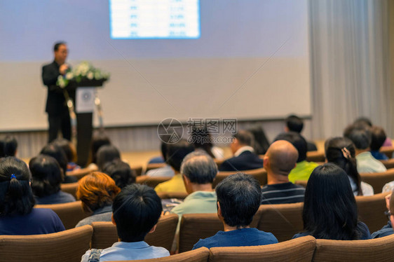 在会议厅的舞台上用讲台聆听演讲者的观众后侧商图片