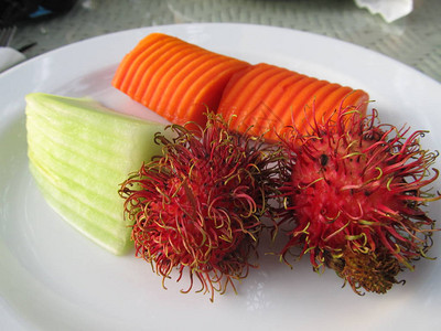 盘子上的异国水果红毛丹和木瓜图片