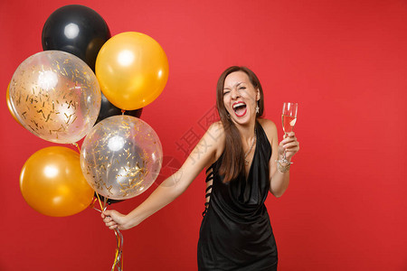 穿着黑色小裙子庆祝尖叫的快乐女孩拿着一杯香槟气球图片