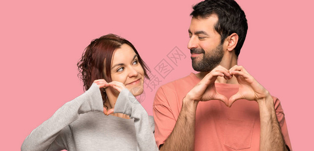 情人节的情侣用双手在孤立的粉红背景上图片