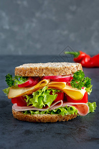 Graham面包三明治加火腿奶酪和深色背景的新鲜蔬图片