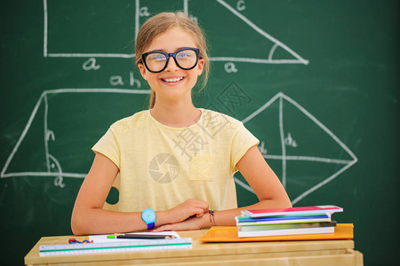 回到学校有趣的美丽女孩坐在教室里反对黑板孩子在学校里有书和配背景图片