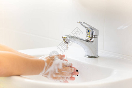 自来水儿童在浴室水龙头下用肥皂洗手图片