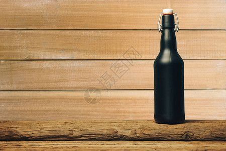 黑啤酒瓶在旧木制桌子图片
