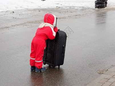 一个小孩拿着一个大手提箱站图片