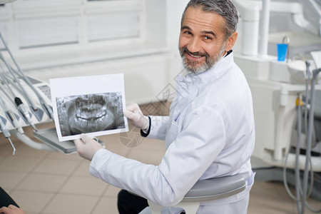 摆姿势和展示下颌的牙科x光片口腔科医生坐在椅子上图片