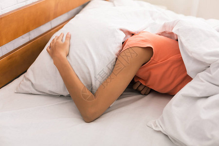 睡眠不足女人用枕头捂着头早上醒来图片