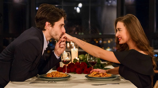 帅男人在浪漫晚餐期间在餐厅亲吻有魅图片
