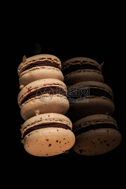 三条花生马卡龙巧克力填充在黑色镜面背景和反射图片