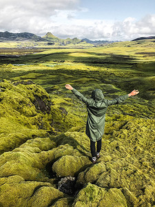 年轻的和平女人在冰岛欣赏苔藓覆盖的草地北极圈野生自然人与自然的联系穿着舒适防水绿图片