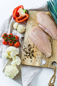 木制砧板上的生鸡胸肉配料保加利亚胡椒西红柿韭菜花椰菜胡椒盐白色图片