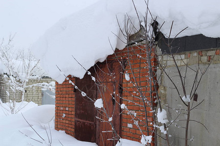 下雪时强风形成的车库屋顶上的雪浪图片