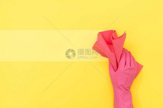 戴橡皮手套手拿着粉色清洁毛巾的女士在黄色背景上孤立图片