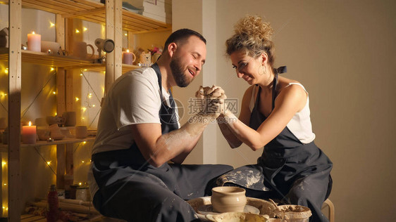 一男女在陶轮上制作陶罐浪漫的情侣手牵图片