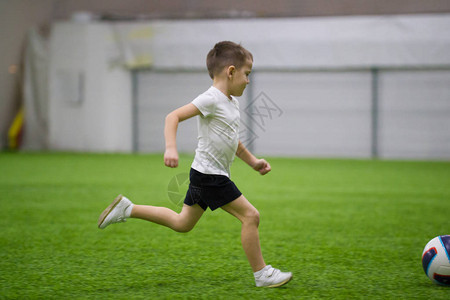 在室内踢足球一个小男孩跑在图片