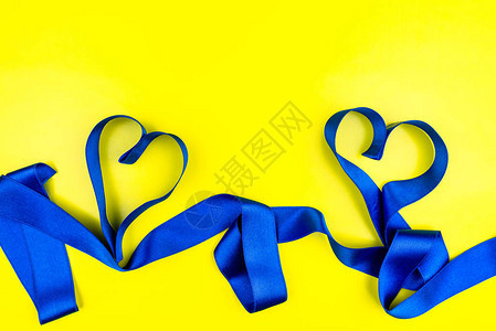 由黄色背景的蓝色讽刺丝带和复制空间所形成的心脏图片