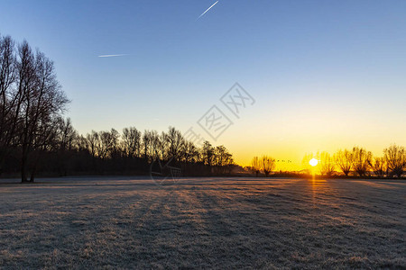 ZoetemeersePlass湖旁边的牧场在太阳升起和天空有美妙图片