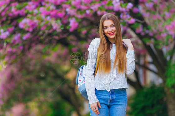 长头发和背包的女孩的可爱笑容在日本樱桃附近图片