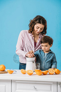 小可爱男孩帮助妈挤压新鲜的橙汁图片