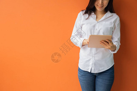 年轻女使用平板电脑智能手机隔绝橙色背景的手机图片