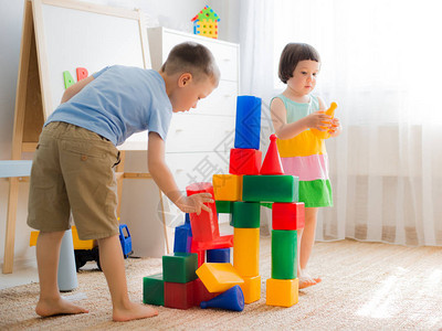 快乐的学龄前儿童玩具积木创意幼儿园的孩子们建造了一座塑料立方体城堡适合家庭的益智玩具兄弟姐妹在房背景图片
