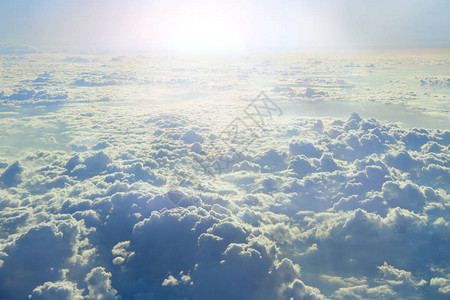 从飞机窗口到阳光照耀在云层上的视图太阳光线照亮的云彩美丽的白云与阳光明媚的光芒与太阳和天空的风图片