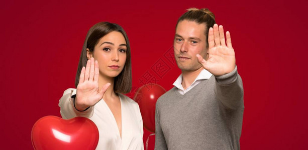 情人节的情侣做出停止手势的姿态否认一种对红色背景的看图片
