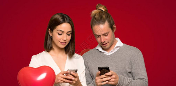 情人节的情侣在红色背景上发信息用移动图片