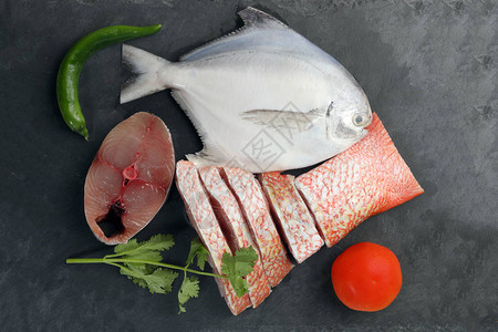 白色鲳鱼西班牙鲭鱼红鲷鱼清洗黑色大理石板背景上的去鳞背景图片