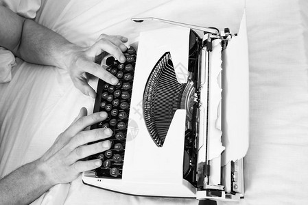 手作家床白色床单工作在新书上作家者习惯于老式机器而不是数字小工具创建新章节使用打字机图片