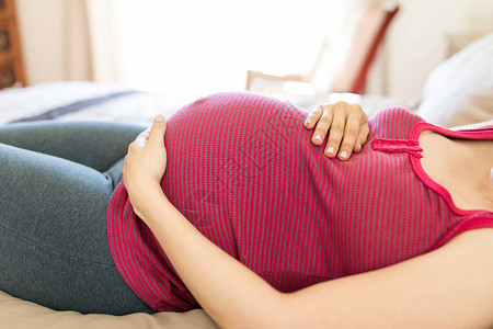 躺在床上时腹部触摸胎儿运动的孕妇中产图片