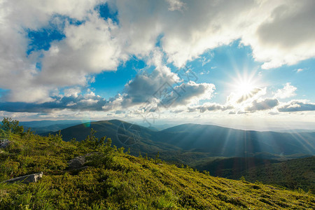 日落时夏山风景草地上的石头云层下遥远的山脊美丽的喀尔图片